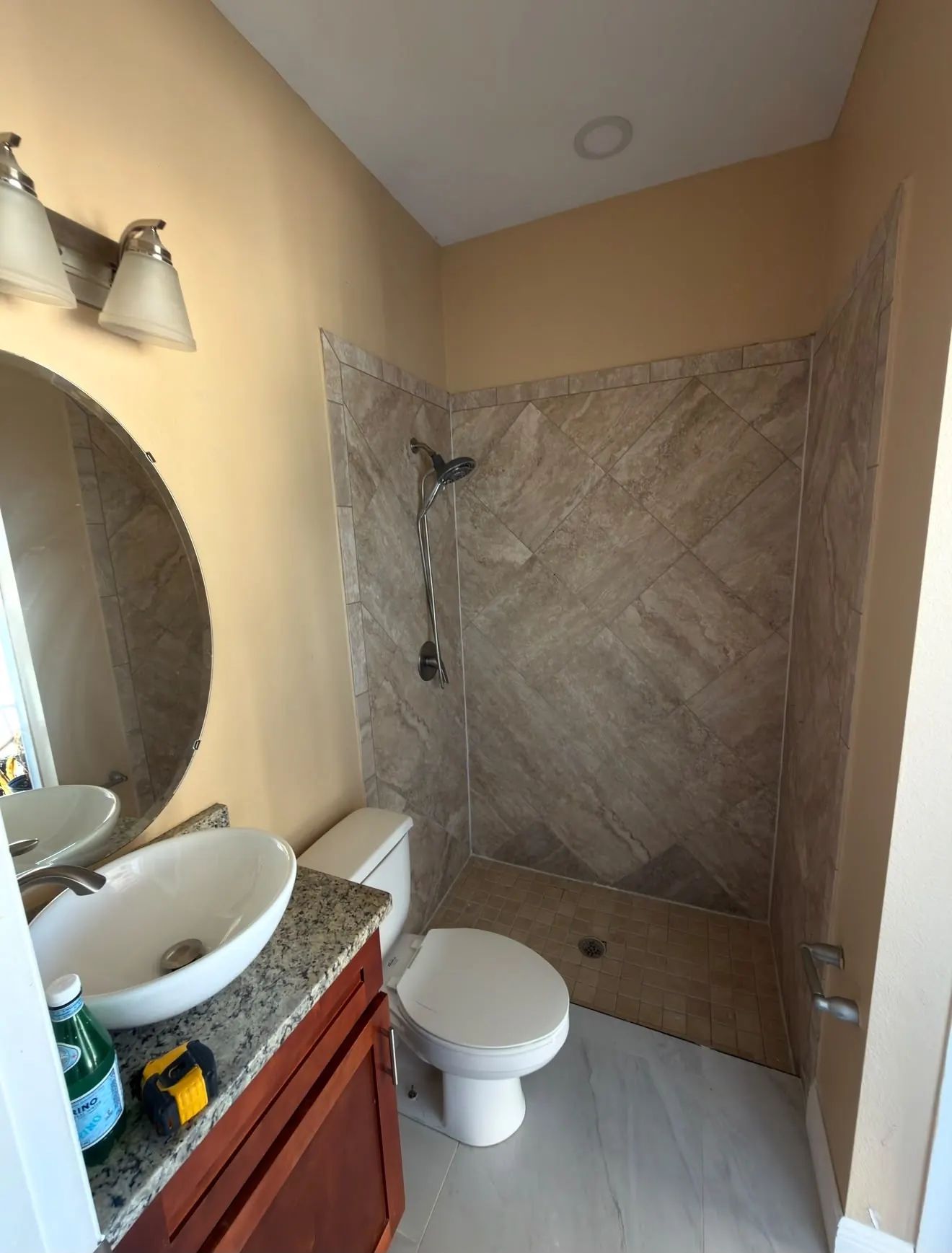 Bathroom with beige travertine tile and cherry vanity before remodeling