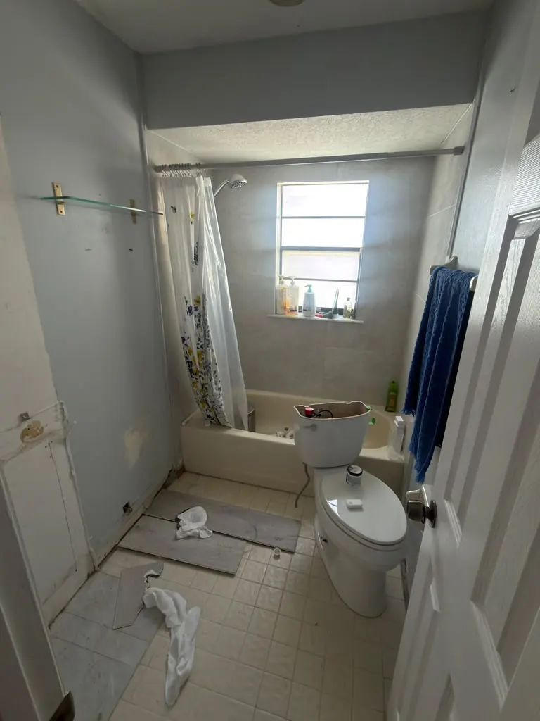 Worn small bathroom with old tub before remodeling
