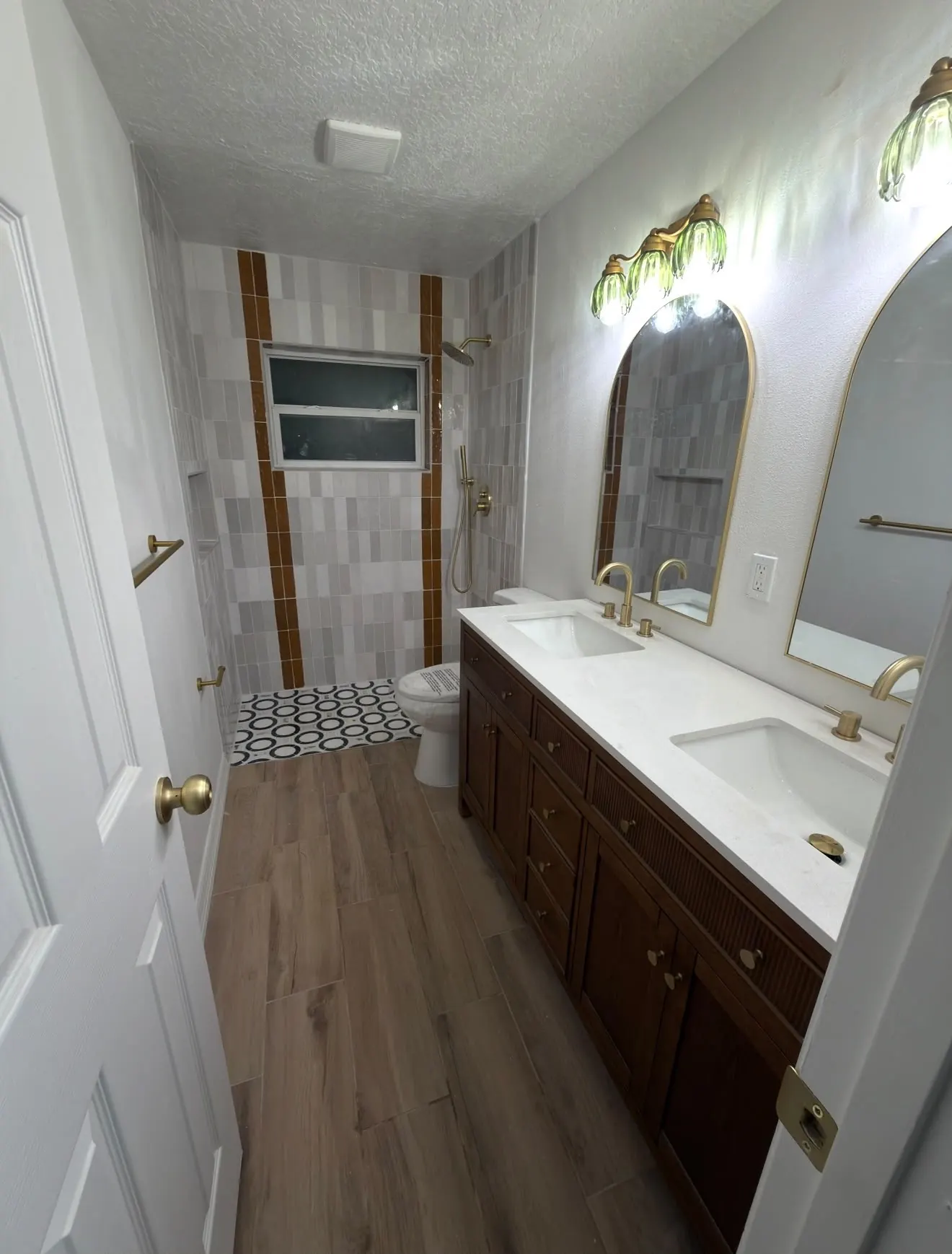 Bathroom finished with grey zellige tile, brass fixtures and a double vanity