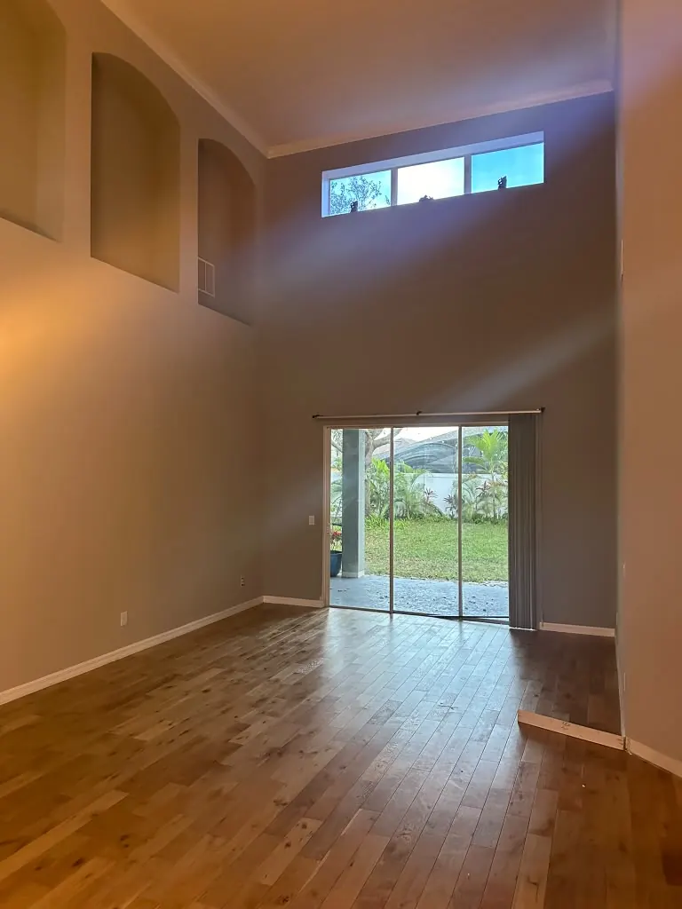 Double-height living room with dated flooring before remodeling