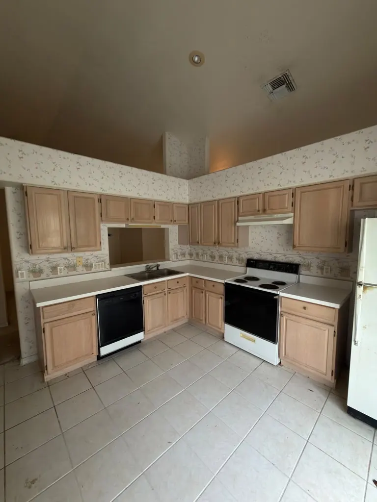 Dated kitchen with light oak cabinets and floral wallpaper before remodeling