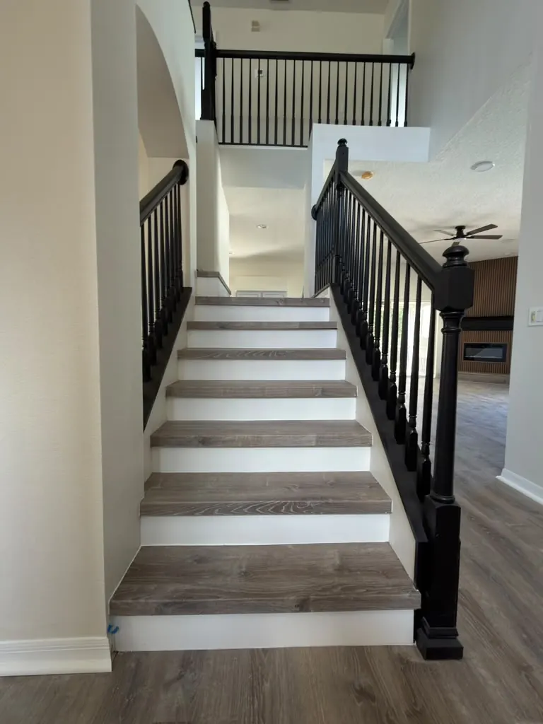 Staircase remodeled with wood-look treads, white risers and a black metal railing